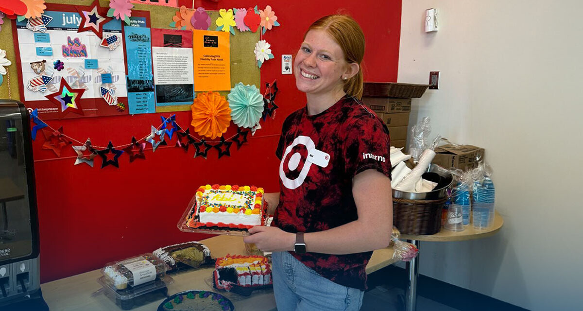 Abi Hopkins hlding a cake, dressed in red, at her internship at Target.