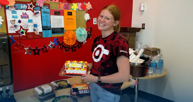 Abi Hopkins hlding a cake, dressed in red, at her internship at Target.