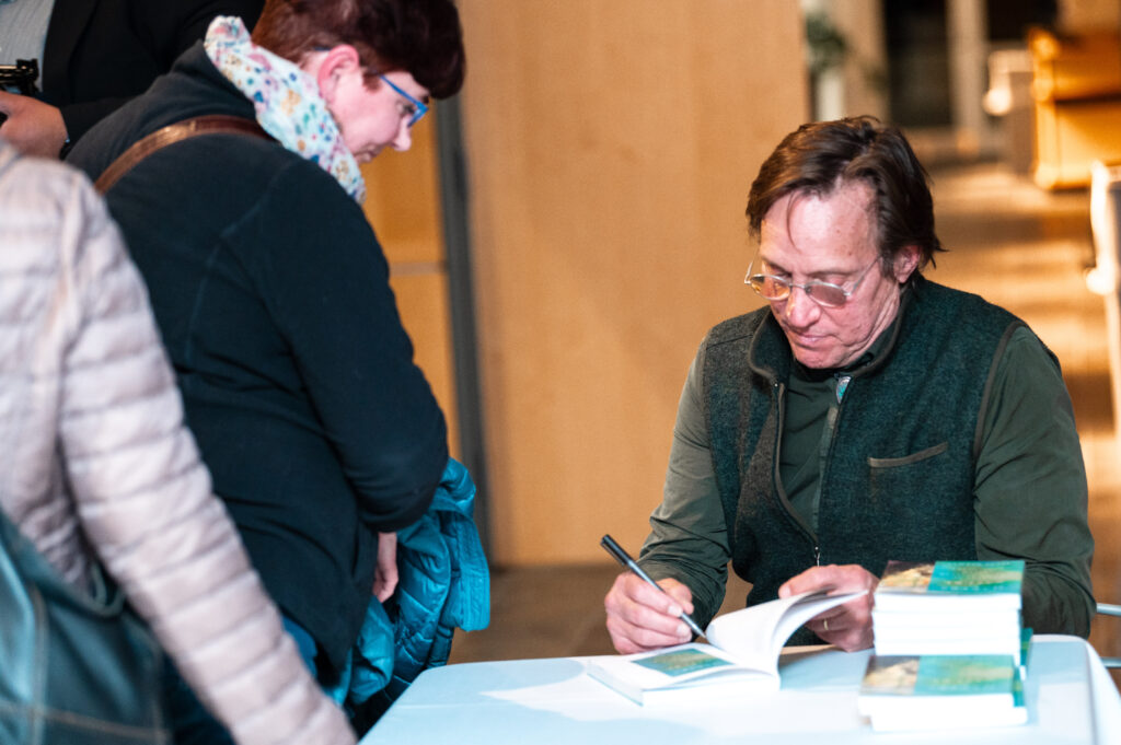 Herman signs a copy of his new book for a friend.